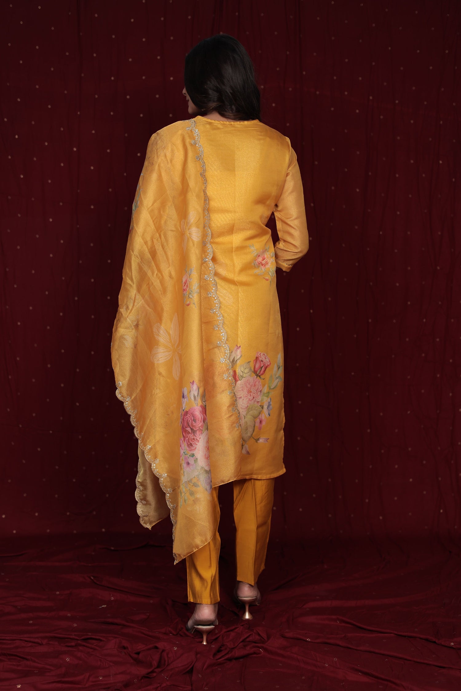 Side profile of model showcasing the flow and fit of the deluxe yellow ethnic suit and organza dupatta.